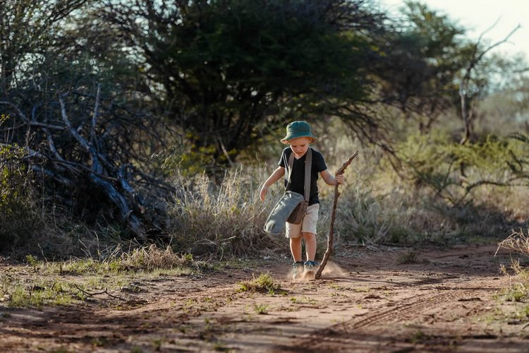 Kleiner Junge wandert durch die Savanne auf Kambaku in Namibia